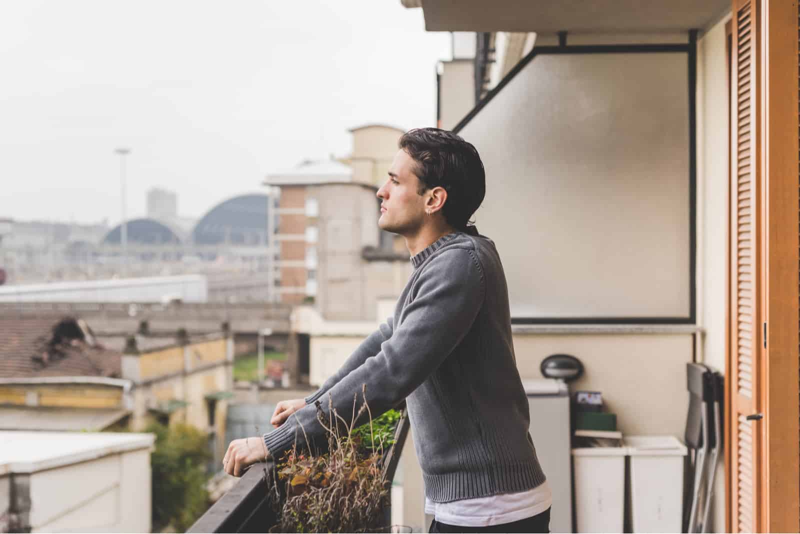Mezzo busto di giovane uomo affascinante in piedi su un balcone