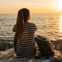 woman sitting on rock by sea