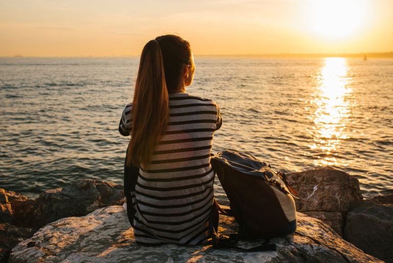 woman sitting on rock by sea