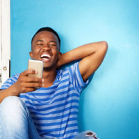 man in a striped t-shirt laughing over a text