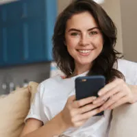 smiling young woman with smartphone on the couch
