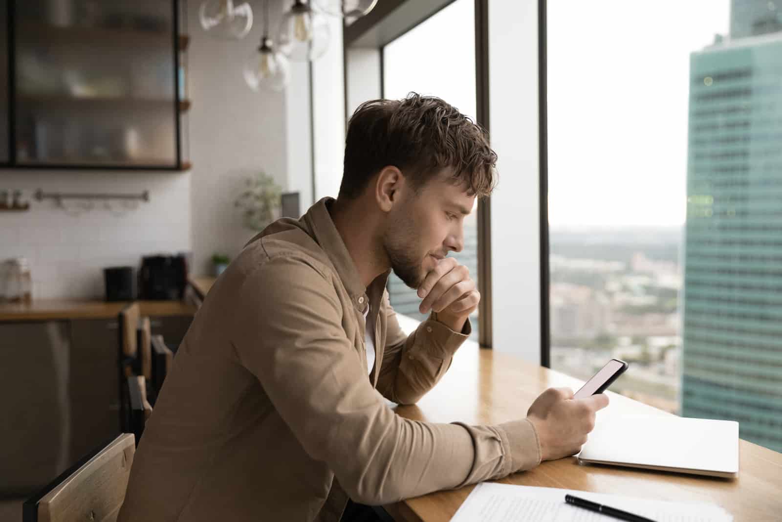 Hombre pensativo mira el móvil reflexionando sobre el trabajo