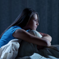 young woman suffering from insomnia while sitting in her bed