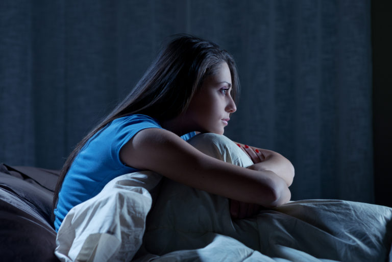 young woman suffering from insomnia while sitting in her bed