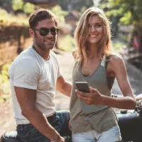 happy young couple with motorcycle on country road
