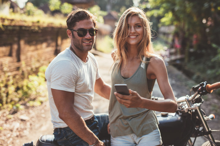 happy young couple with motorcycle on country road