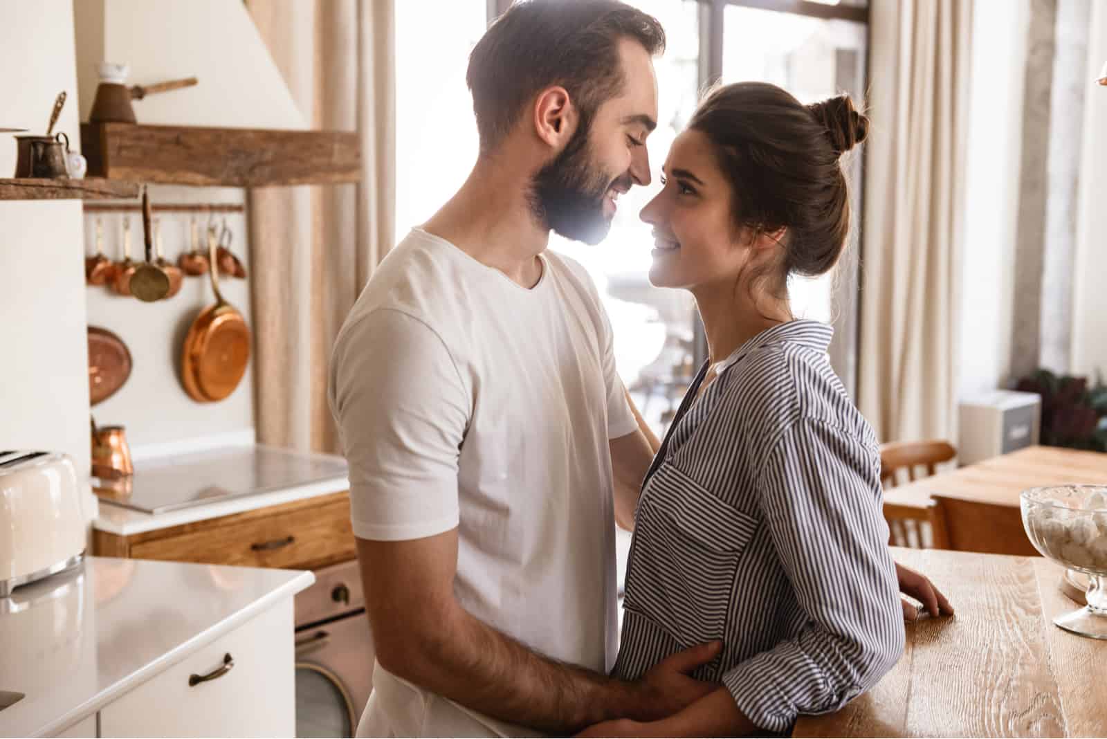 a man and a woman stand embracing in the kitchen
