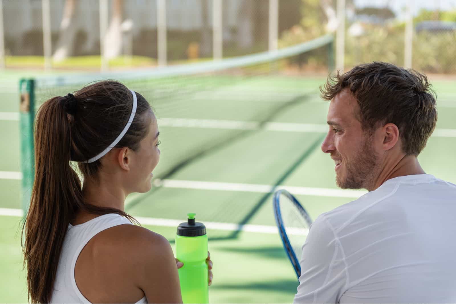 a man and a woman talking on a tennis court