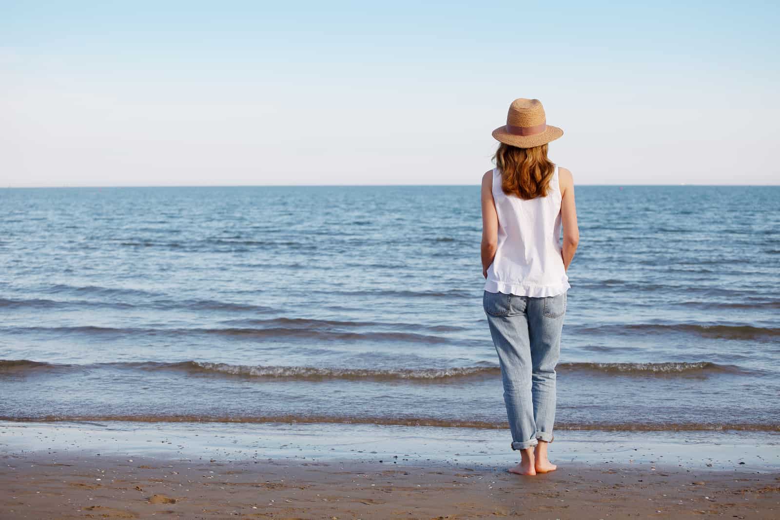 una donna con un cappello in testa apparecchia sulla spiaggia