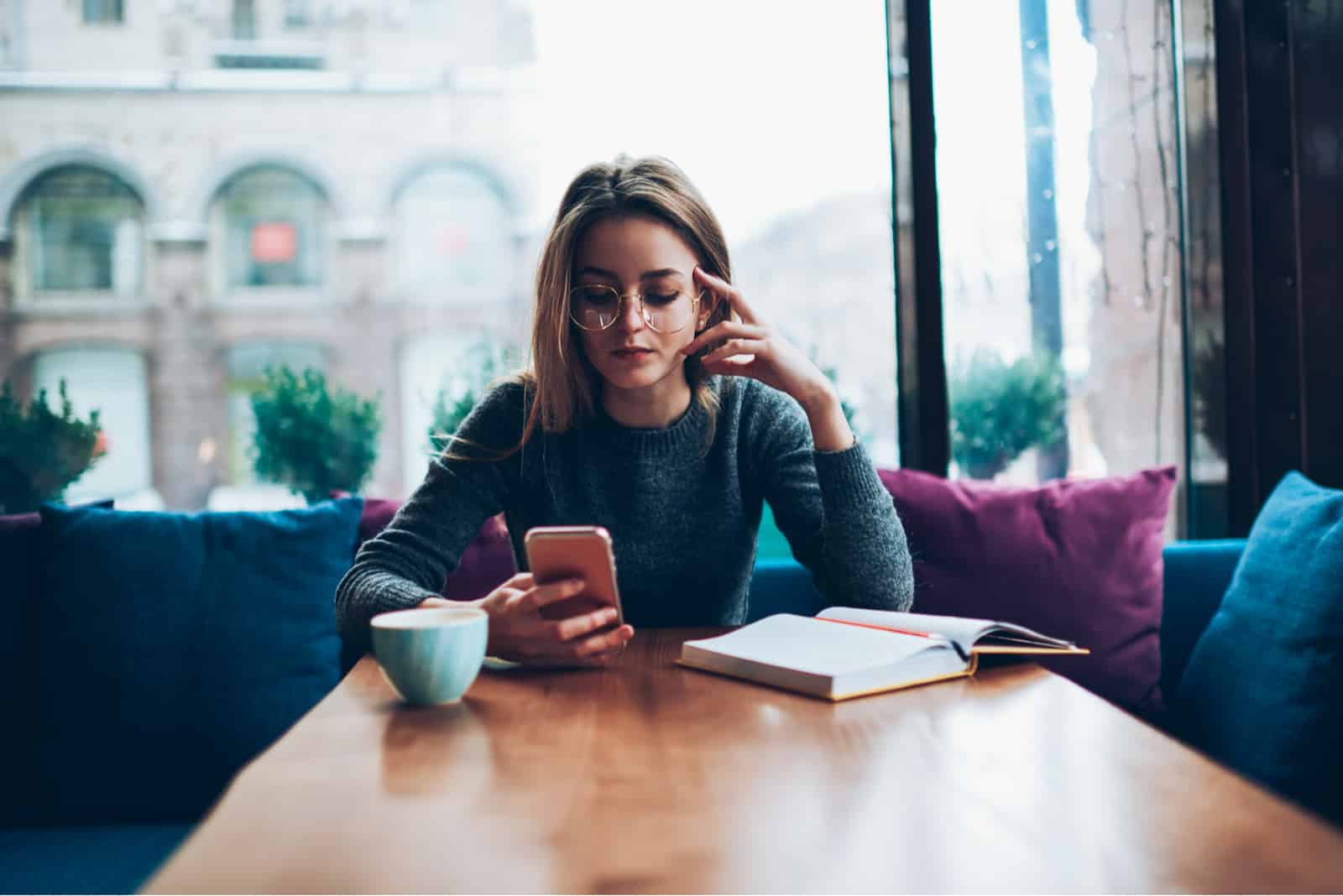 una mujer imaginaria sentada en un café y pulsando un teléfono