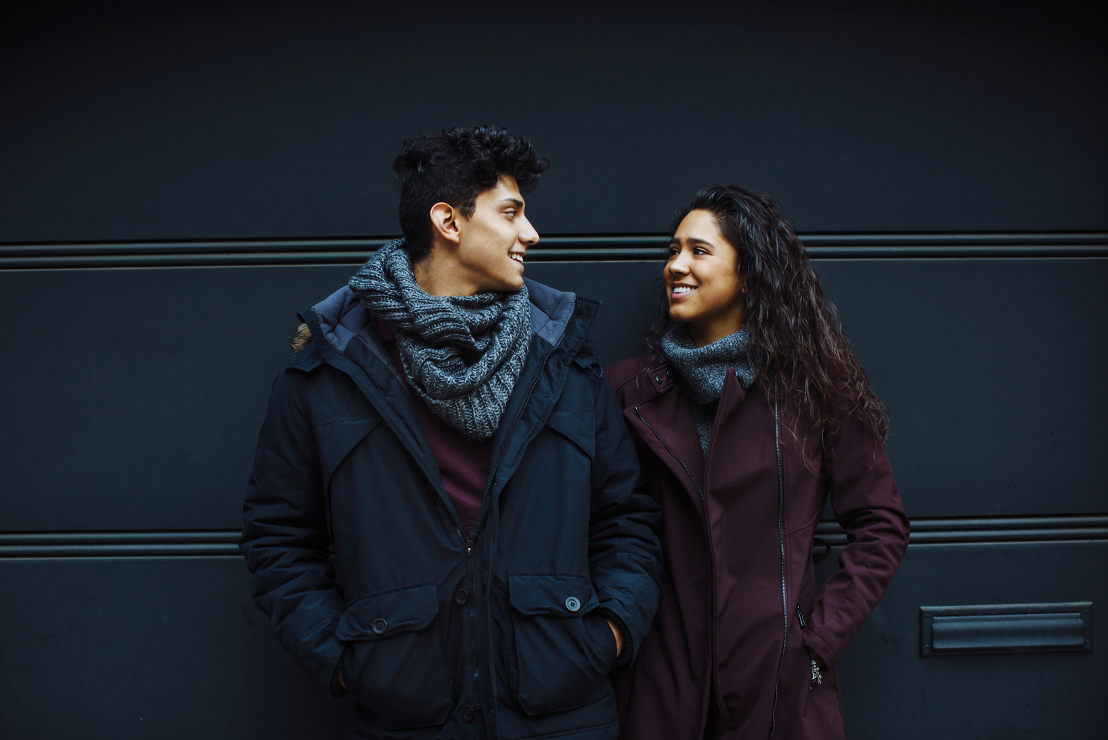 casal em pé no exterior com fundo azul escuro