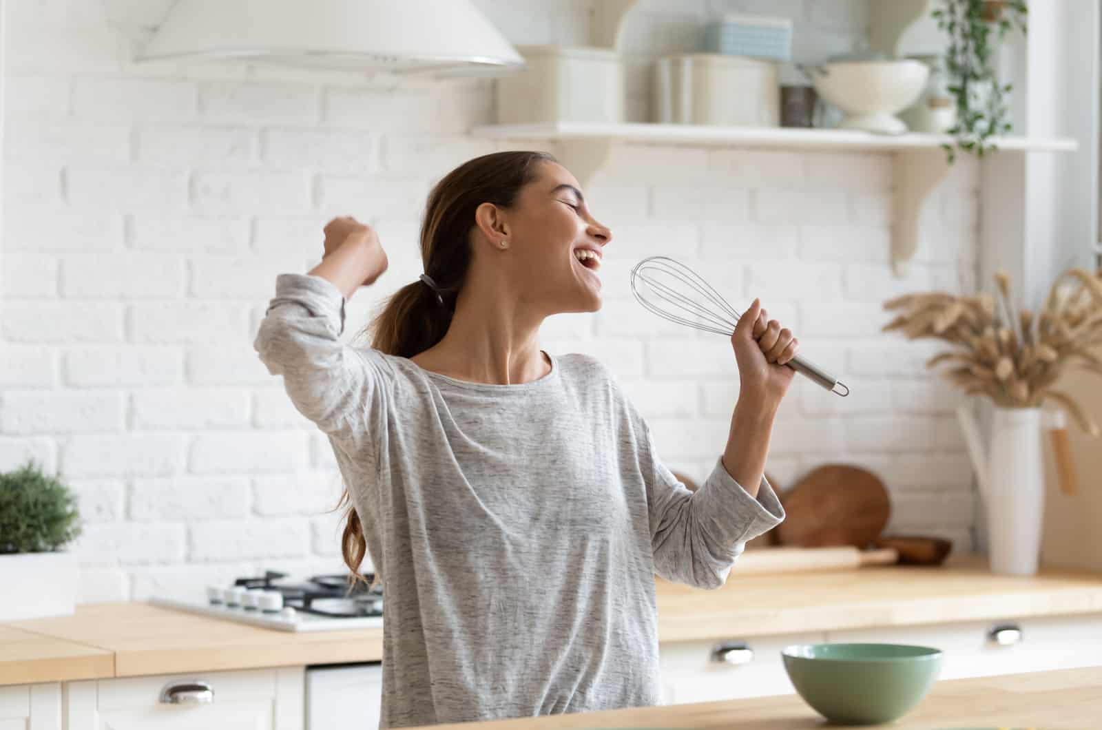 mulher feliz a cantar na cozinha