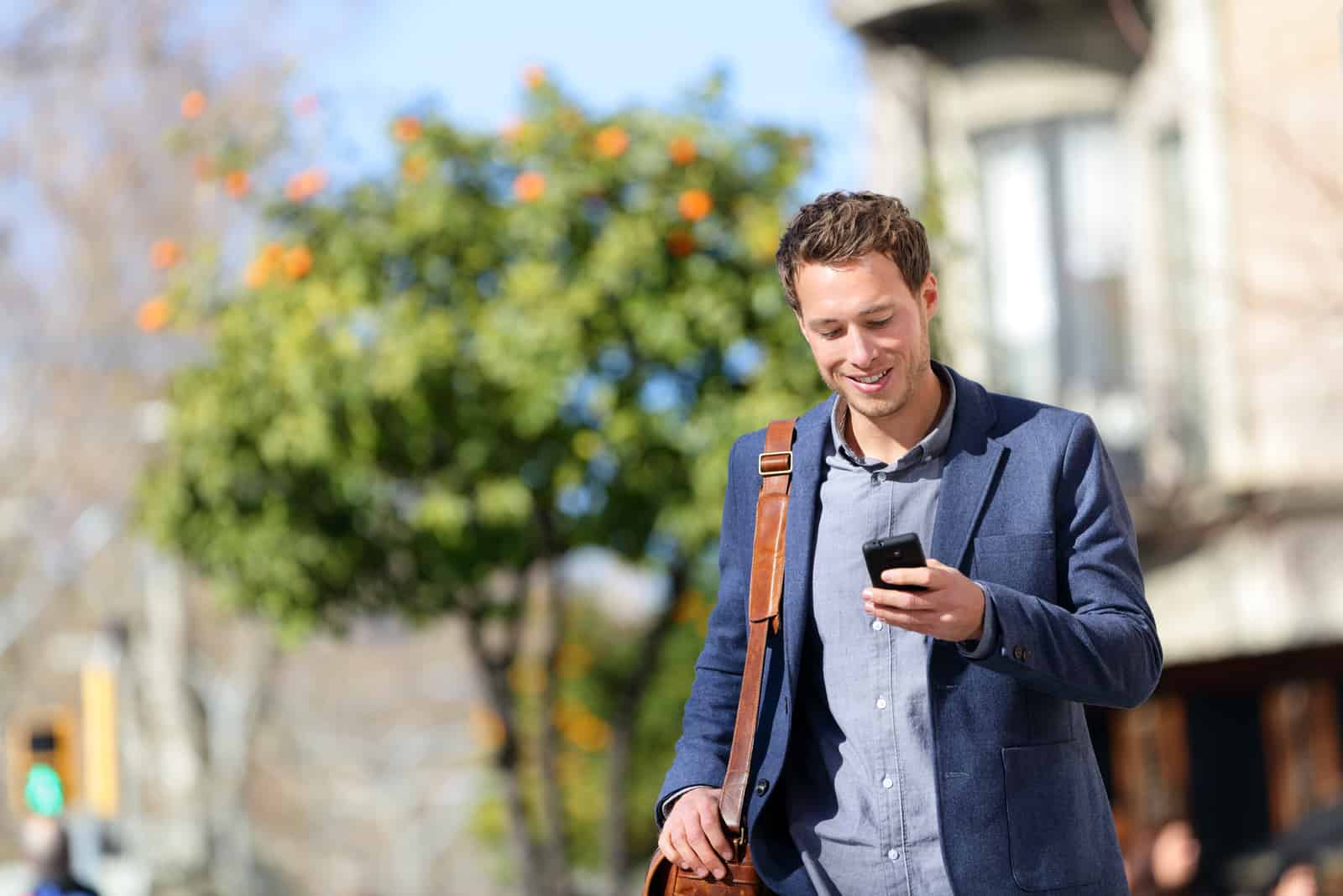 uomo che legge i suoi messaggi mentre cammina