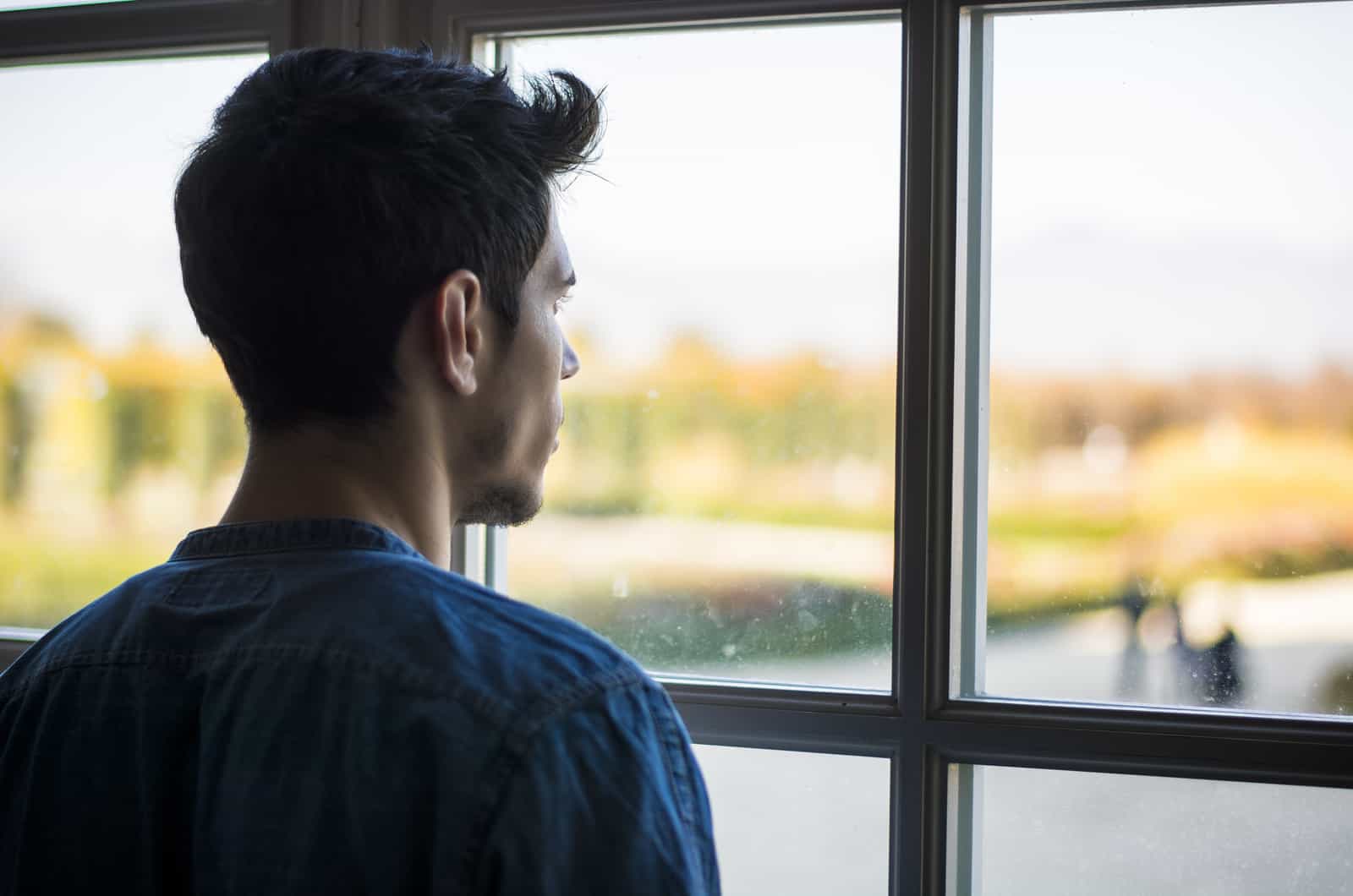 thoughtful handsome young man looking away out of window