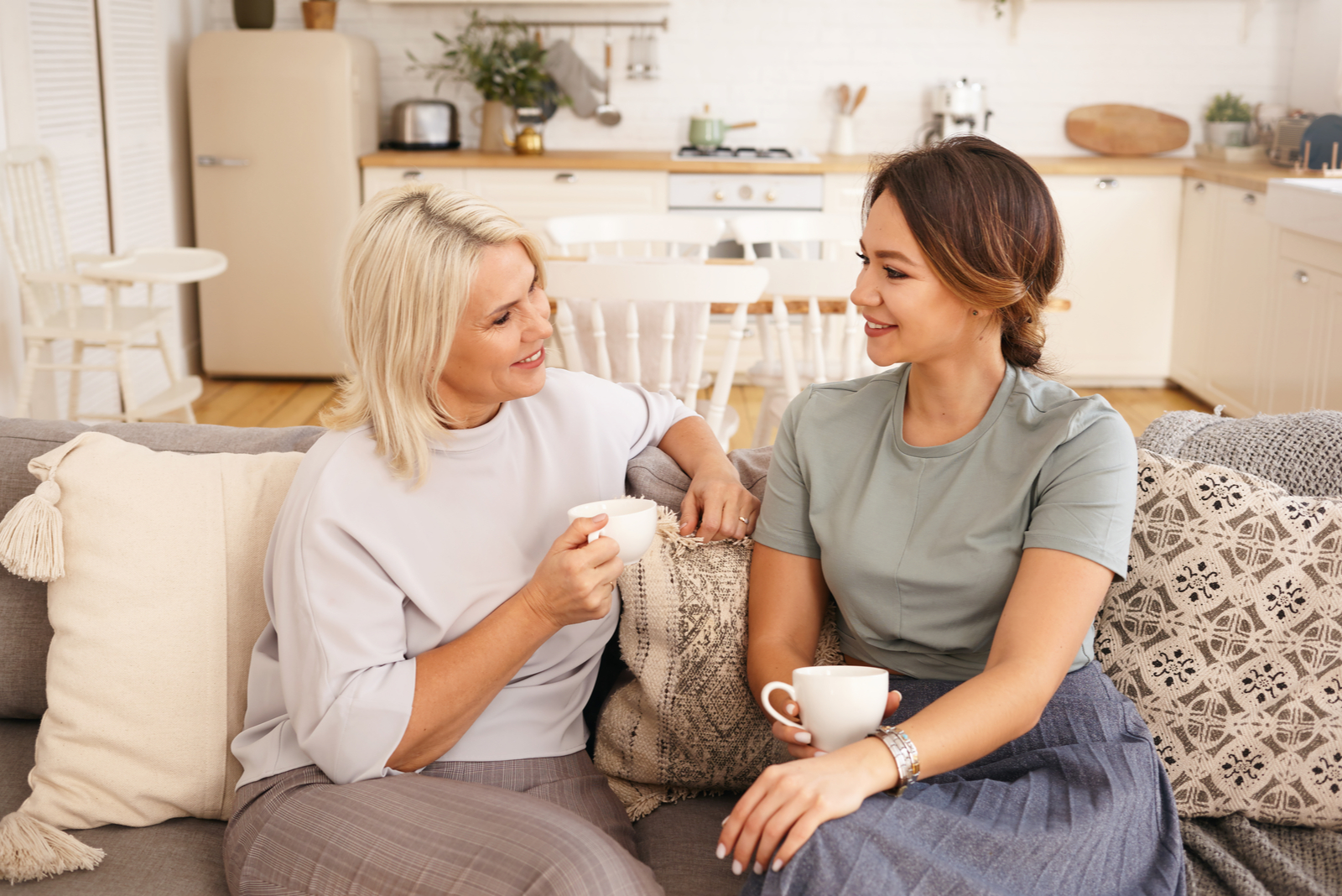 two women sit on the couch and talk 