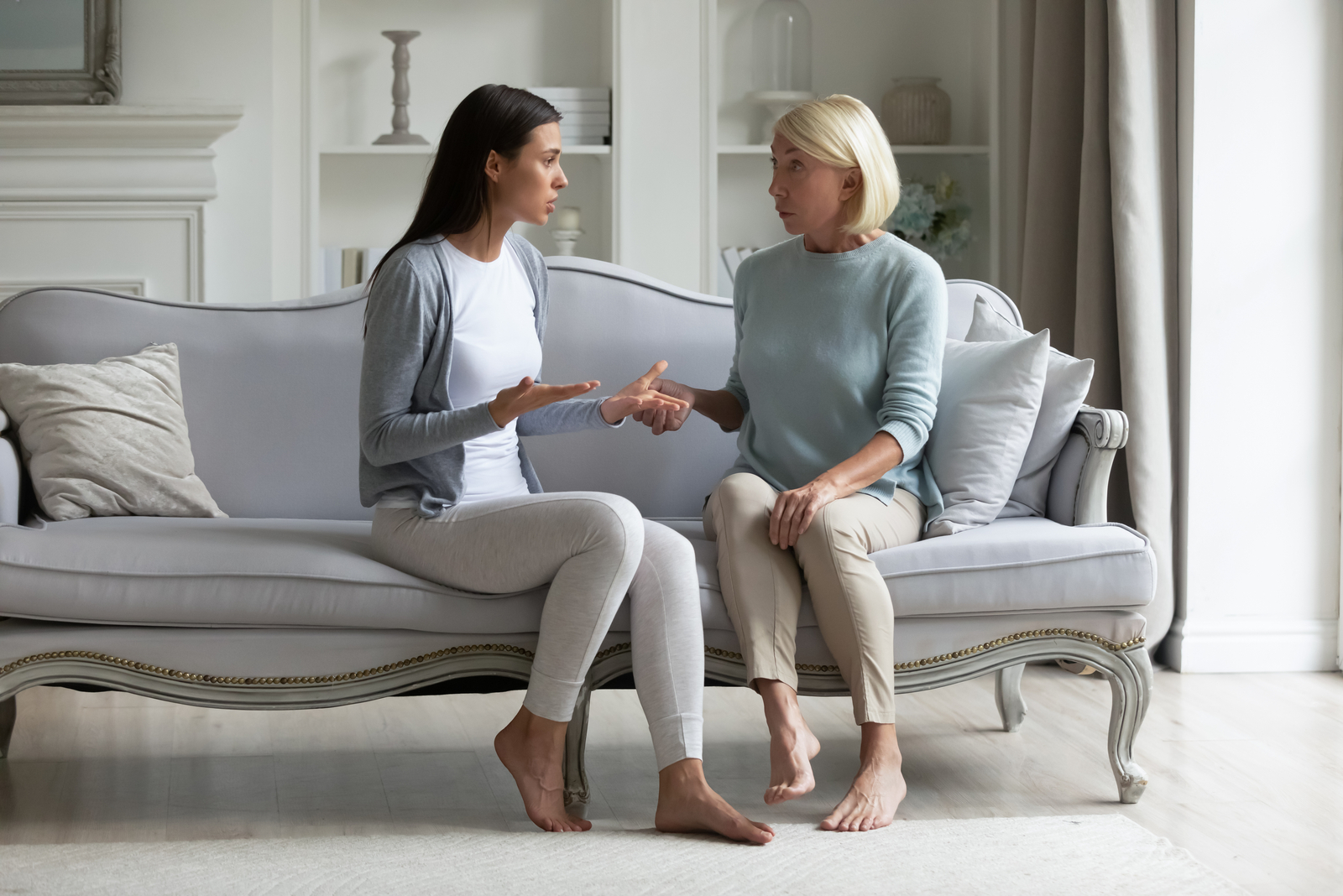 two women sit on the couch and talk