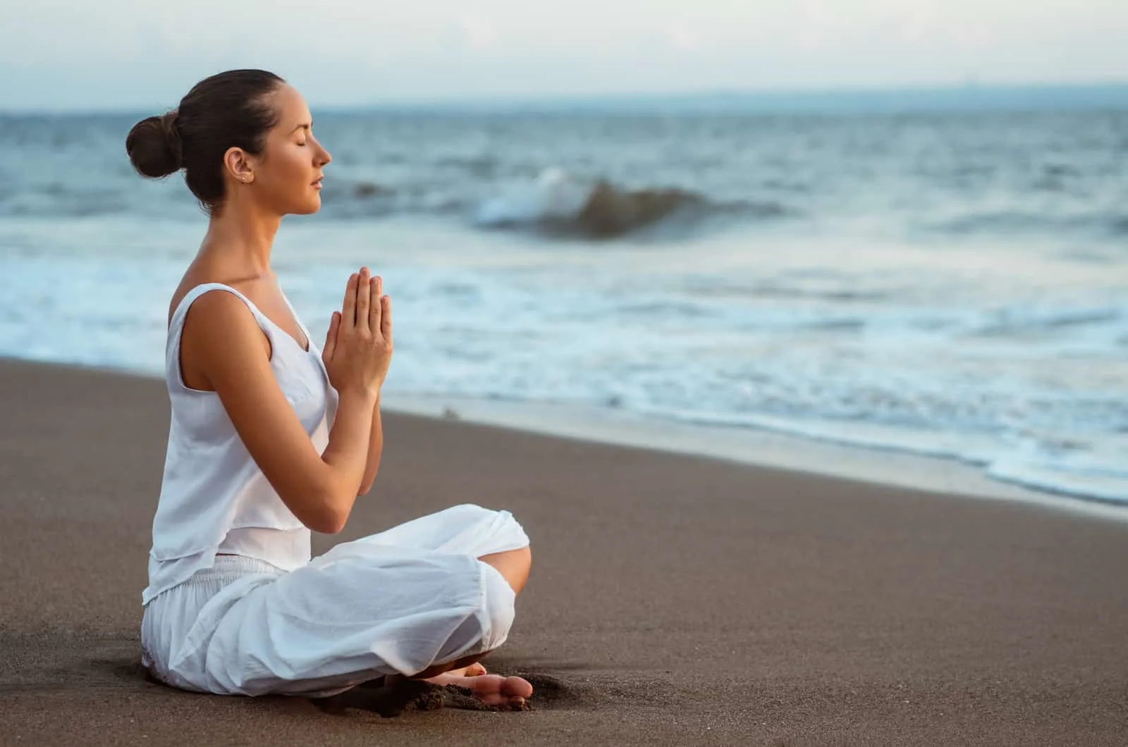 woman meditating by beach