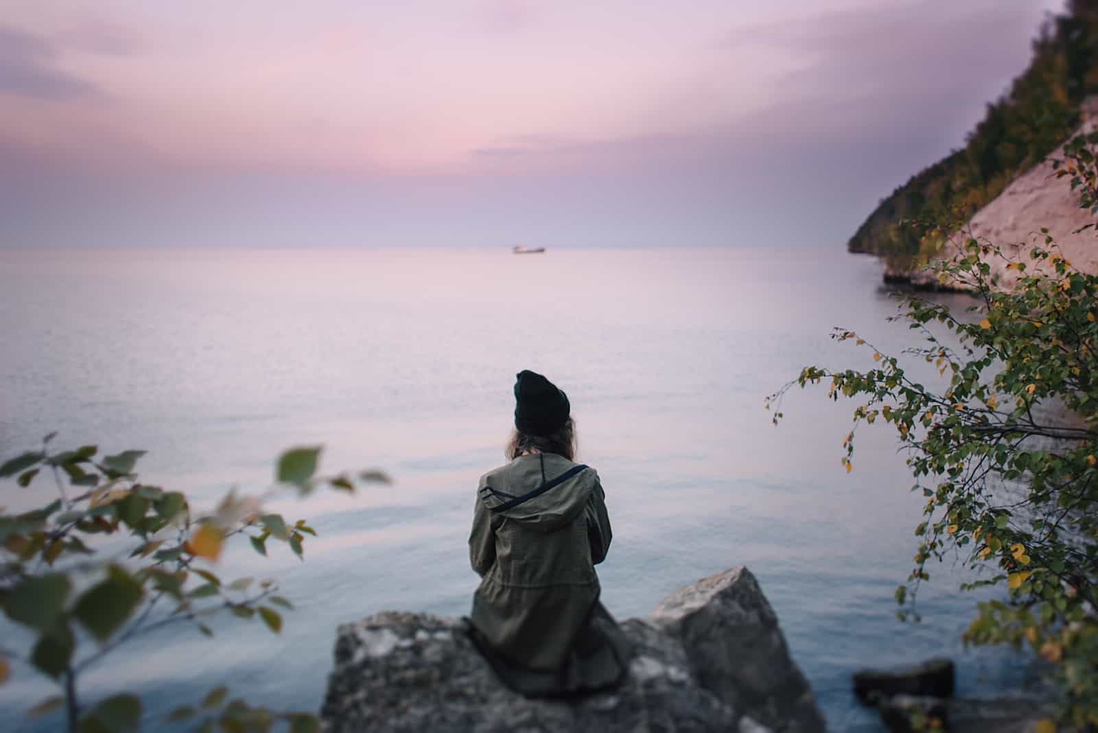 donna seduta su uno scoglio in riva al mare