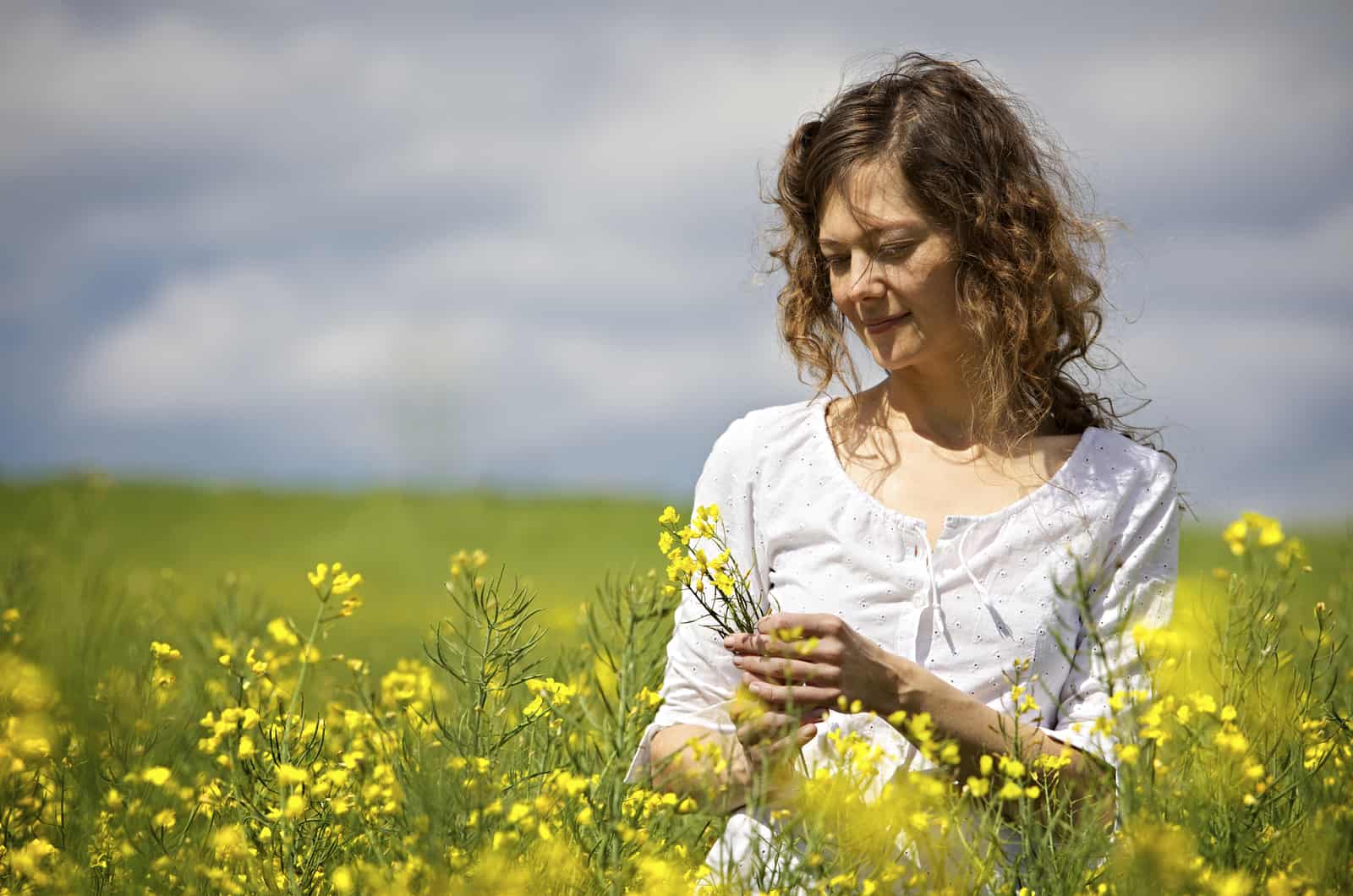 mulher de pé num campo de flores