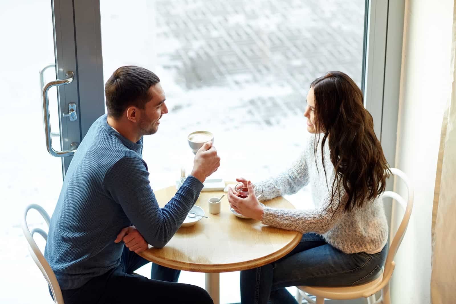 pareja de jovenes hablando en un cafe