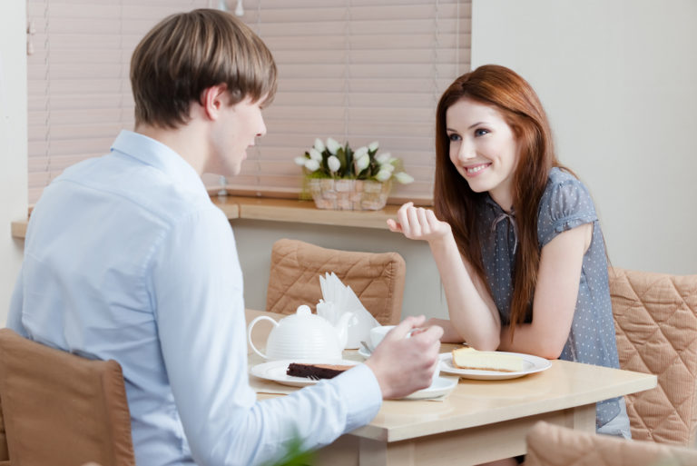 hombre y mujer sonrientes sentados a la mesa y hablando