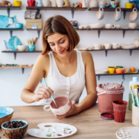 woman decorating a mug in pottery