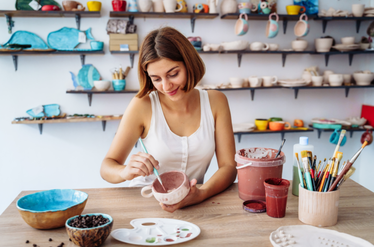 woman decorating a mug in pottery
