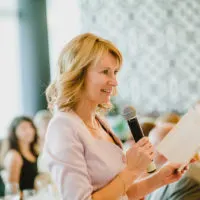 smiling woman with blond hair gives a speech at a wedding