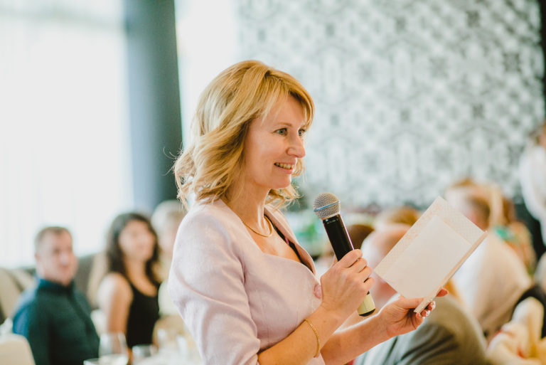 mujer sonriente con el pelo rubio da un discurso en una boda