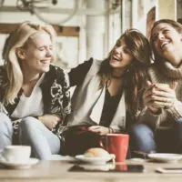 smiling female friends are sitting and talking