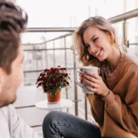 man and woman drinking coffee on a balcony