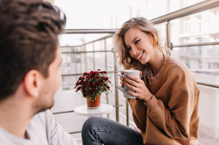 man and woman drinking coffee on a balcony