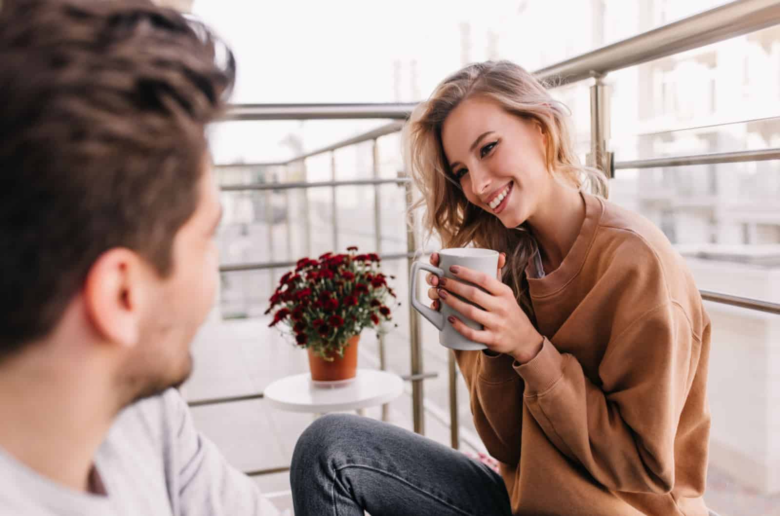 man and woman drinking coffee on a balcony