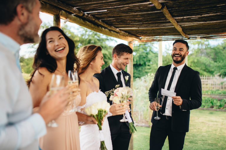 a smiling man gives a speech at a wedding