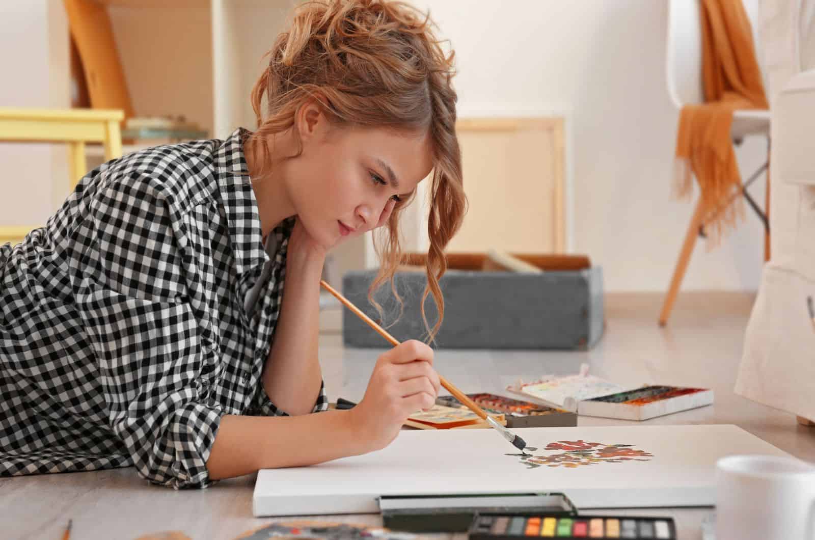 Giovane artista donna che dipinge un quadro in studio