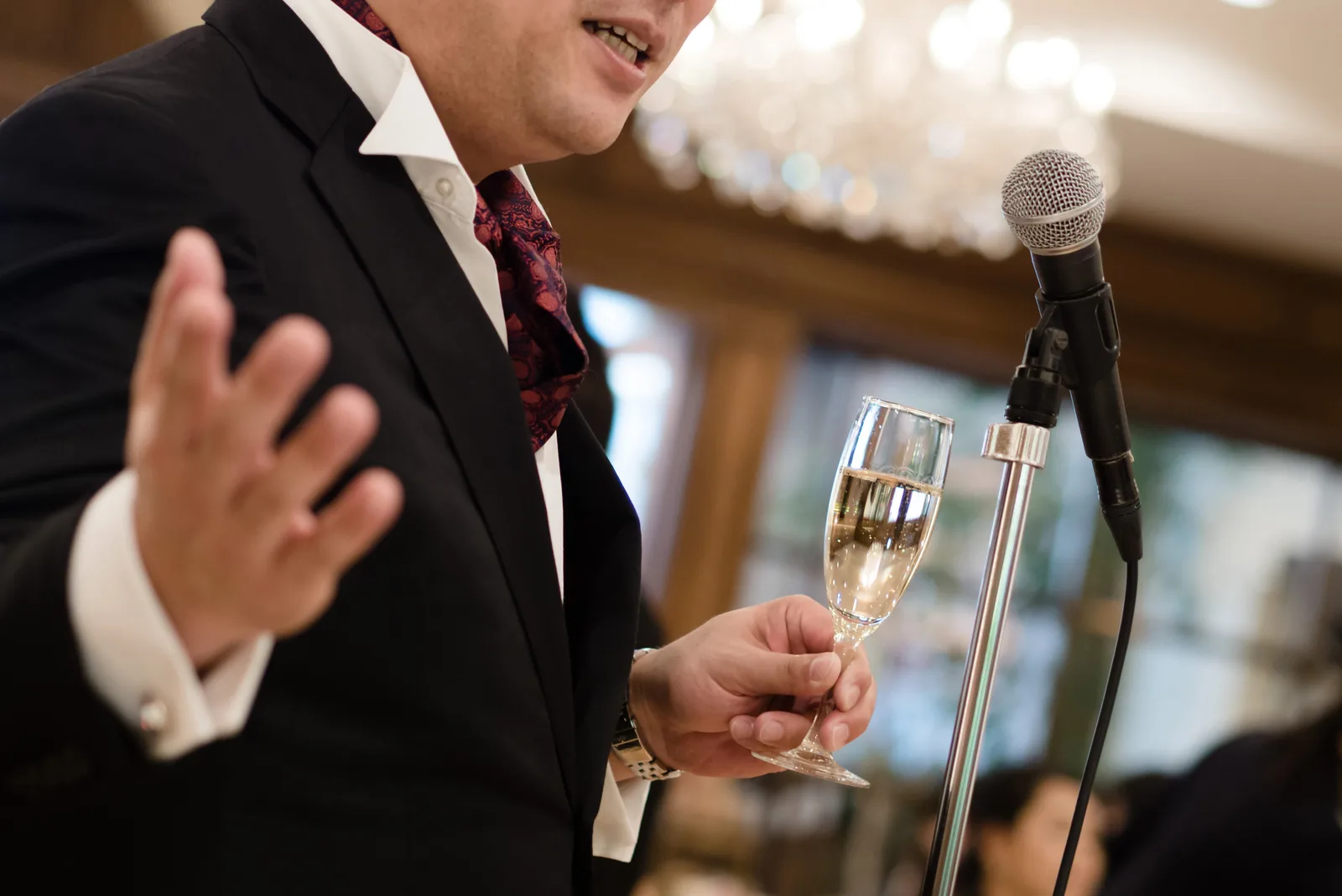 a man holds a glass of wine and gives a speech