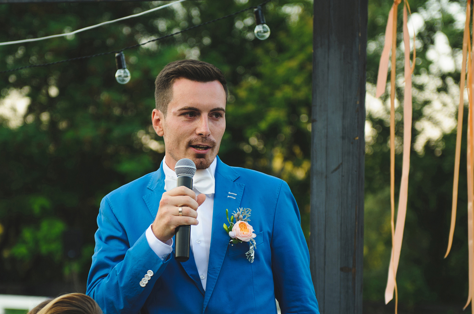 a man in a blue suit speaks at a wedding