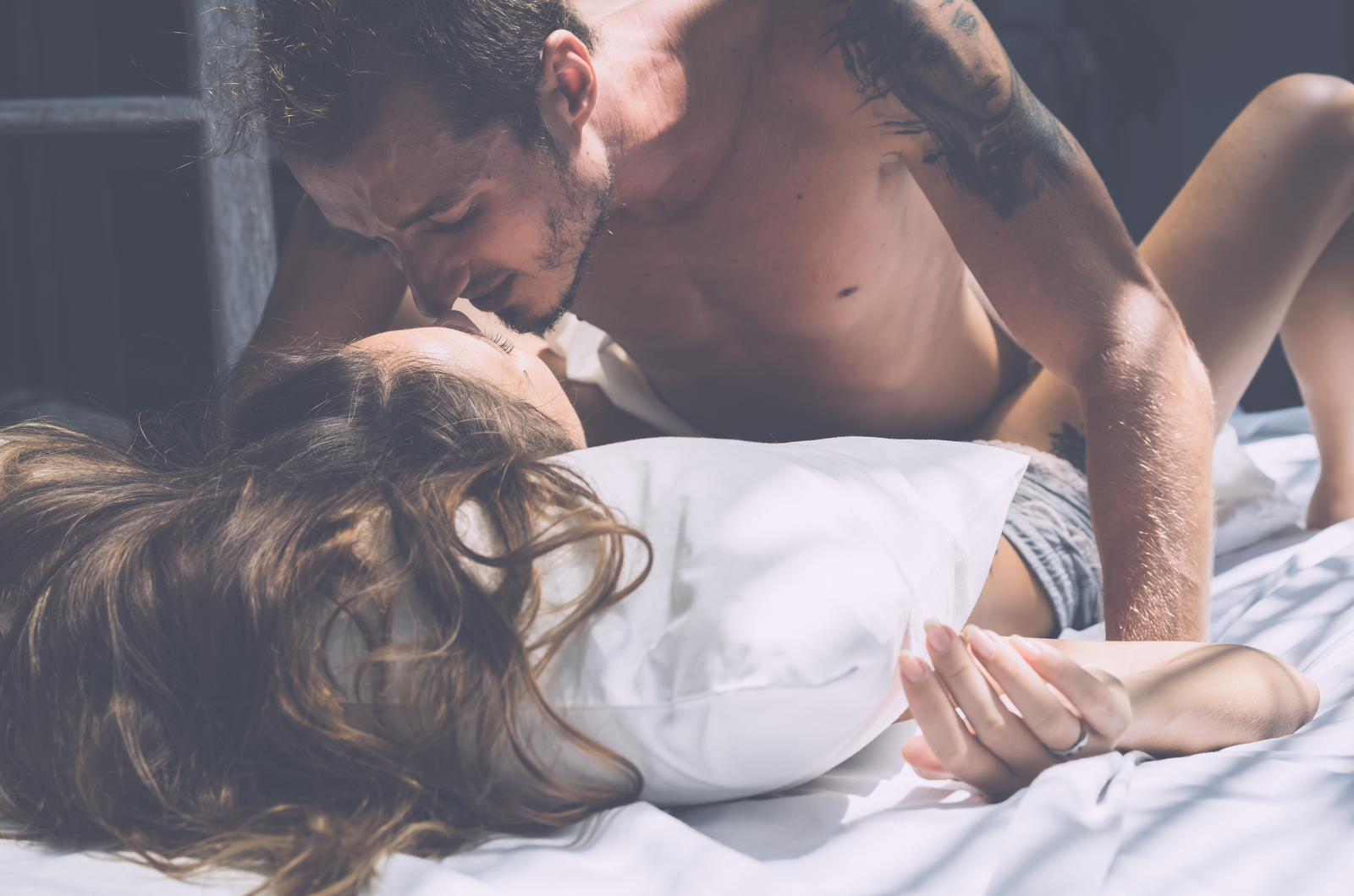 un hombre besa a una mujer en la cama