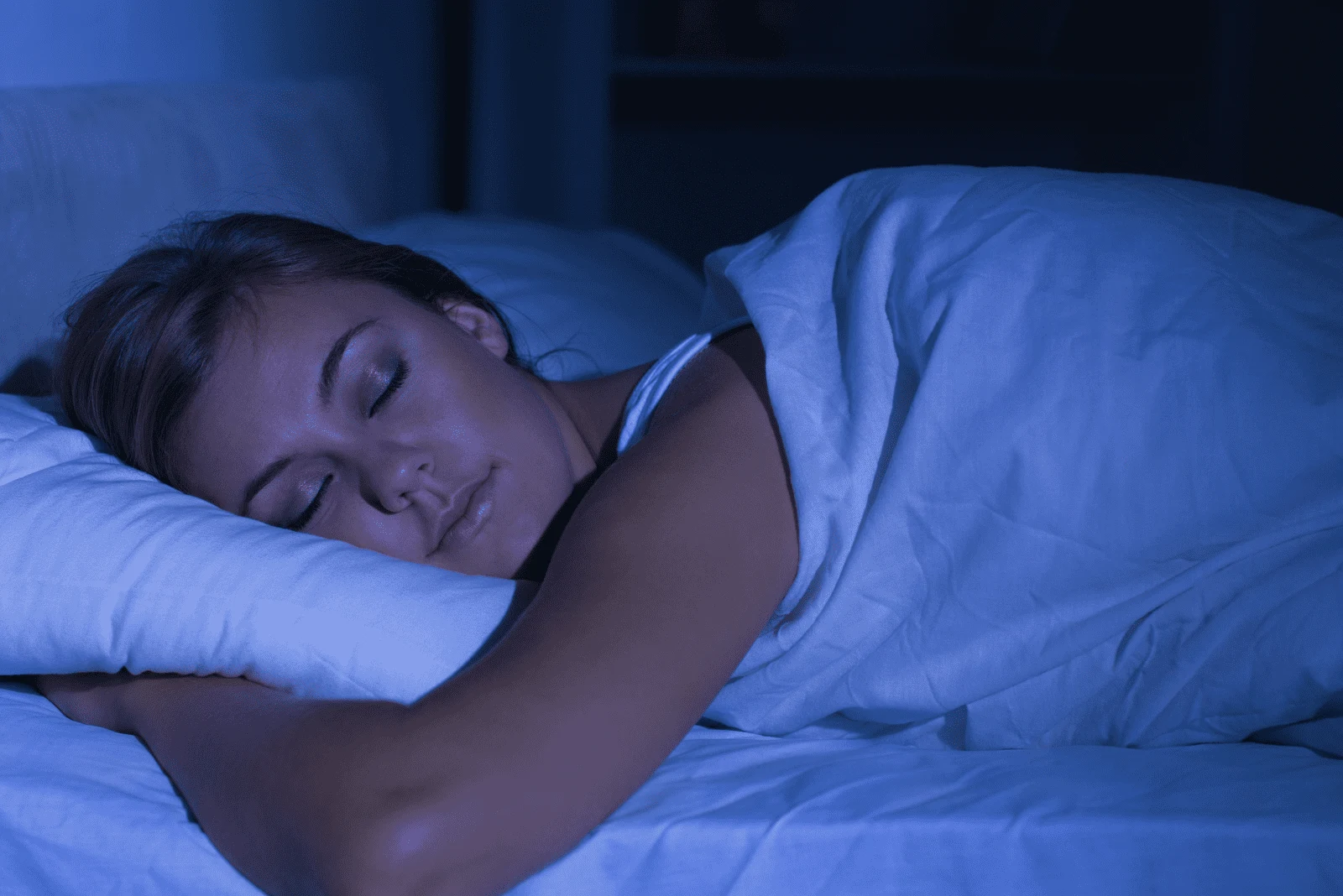 a woman hugging a pillow while sleeping in bed