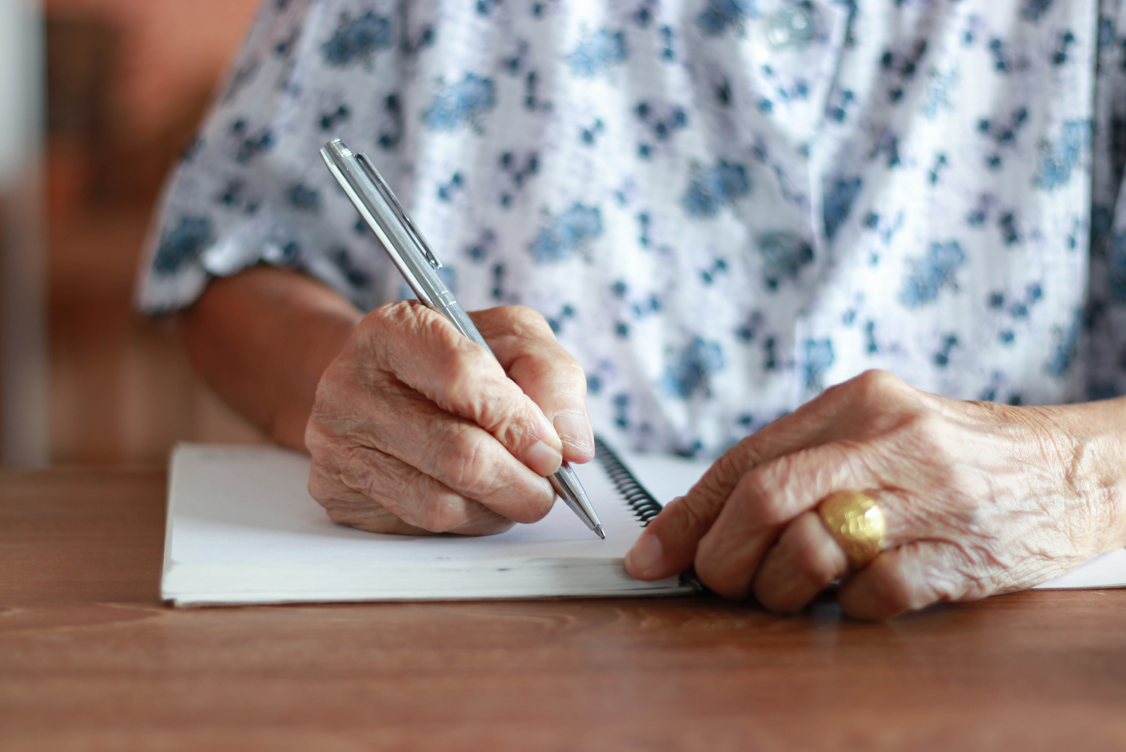 a woman sits at a table and writes a letter