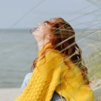 happy woman in yellow sitting on beach