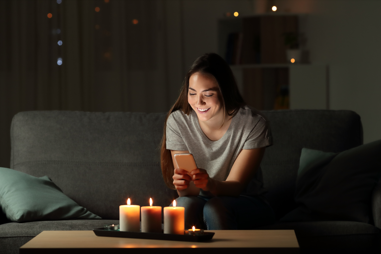 chica sentada en el sofá en la oscuridad en su teléfono