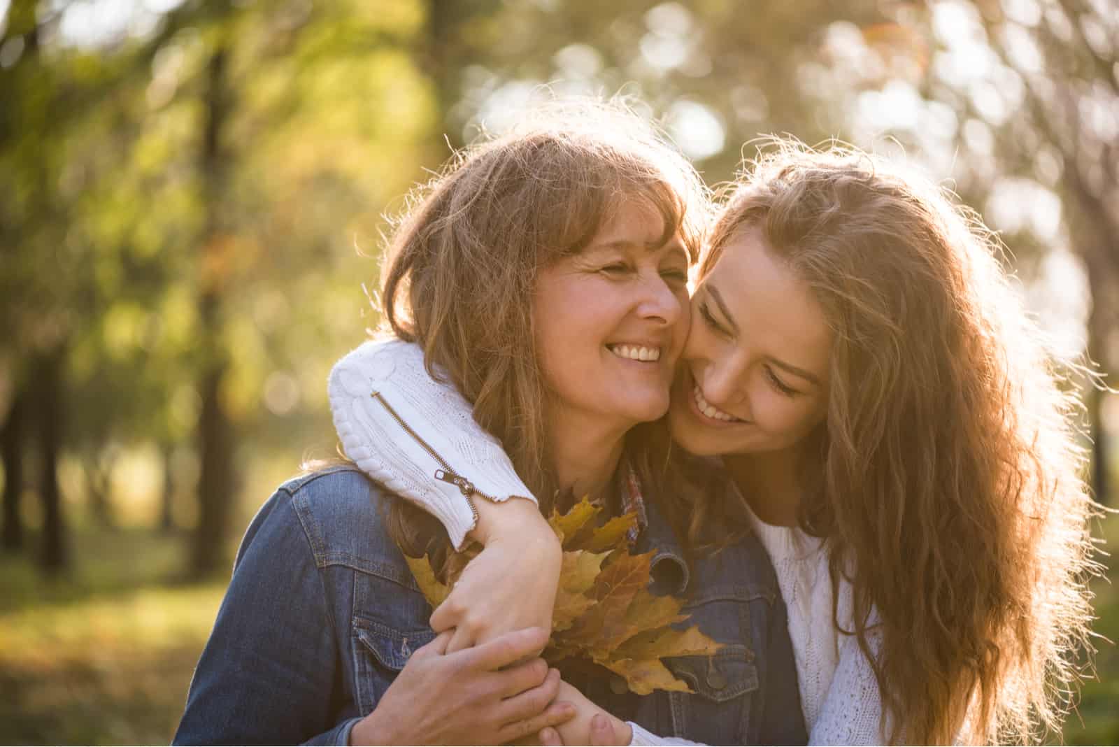 mother and daughter hugging outside in park