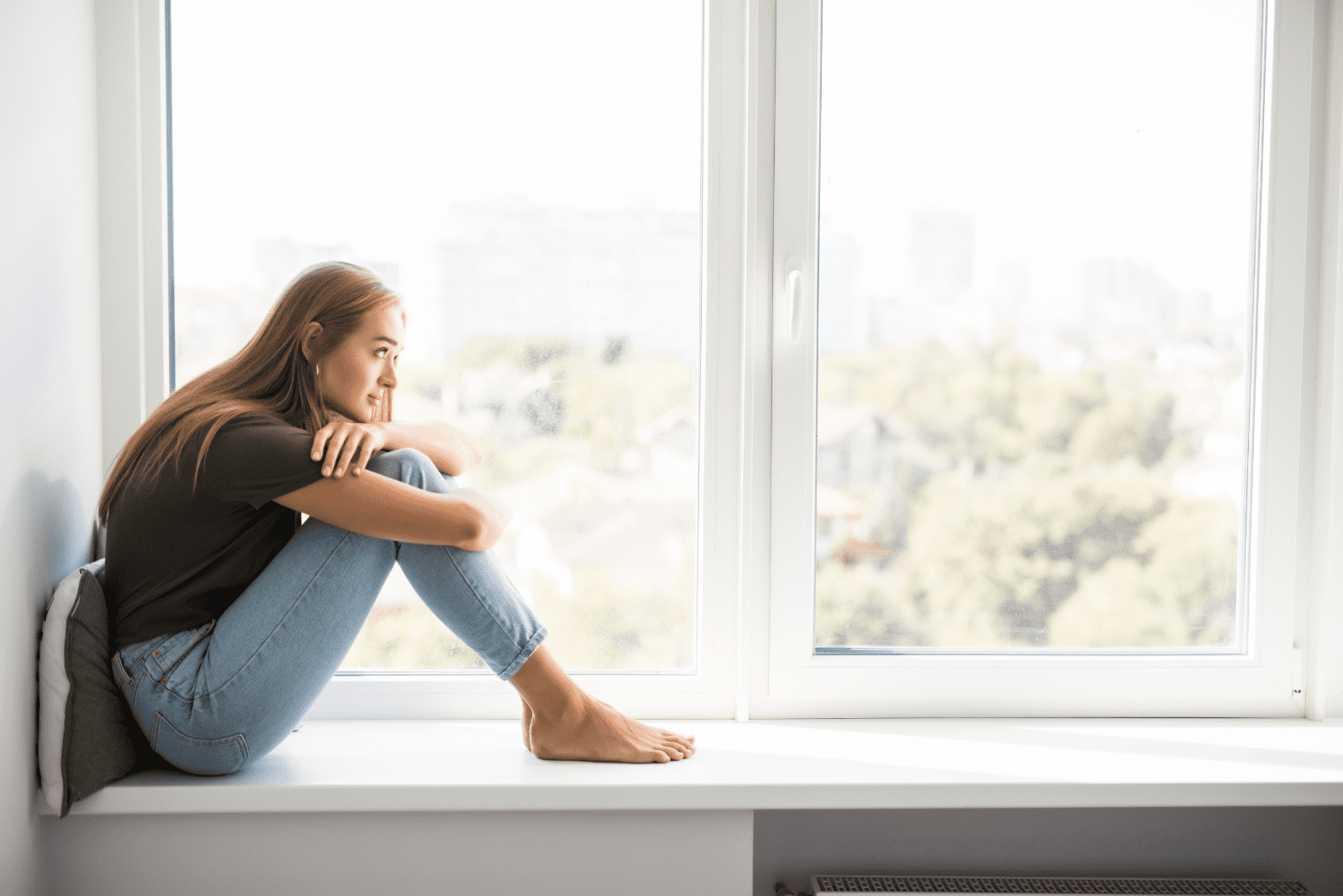 pensive woman sits by the window