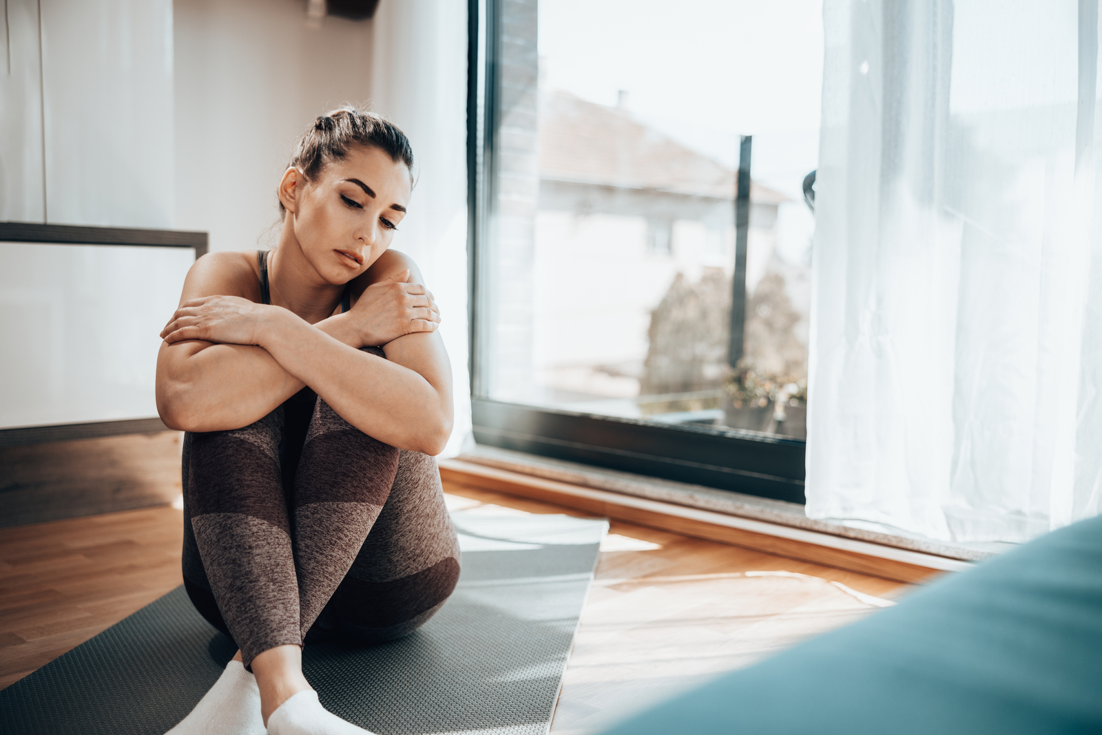 morena triste sentada num tapete de ioga