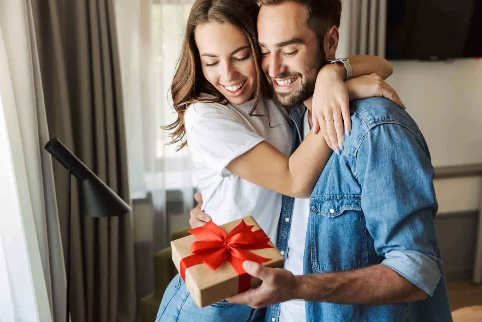 smiling man and woman embracing while he holds a gift