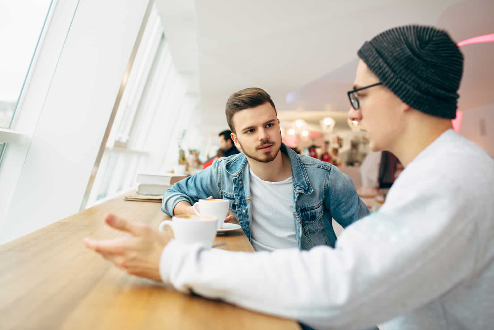 dois amigos estão sentados num café a conversar