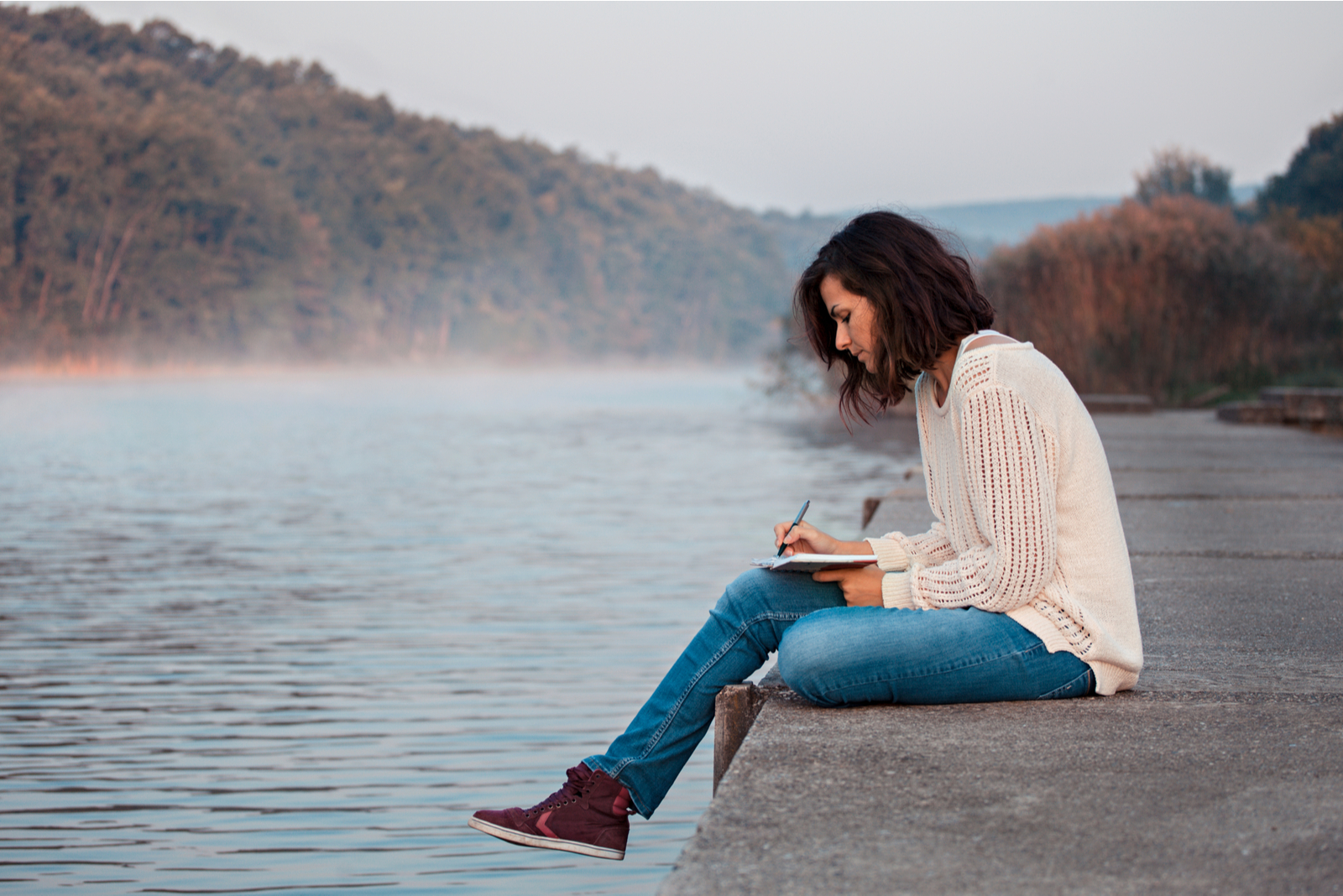 woman sitting on dock by lake