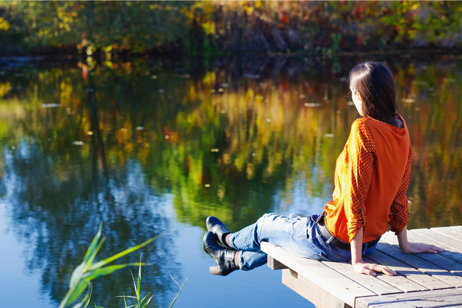 woman sitting on dock looking at lake