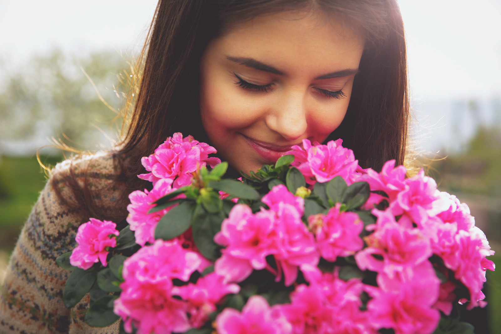 mulher a cheirar flores cor-de-rosa